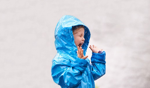 Picture of girl laughing in rain wearing a blue coat