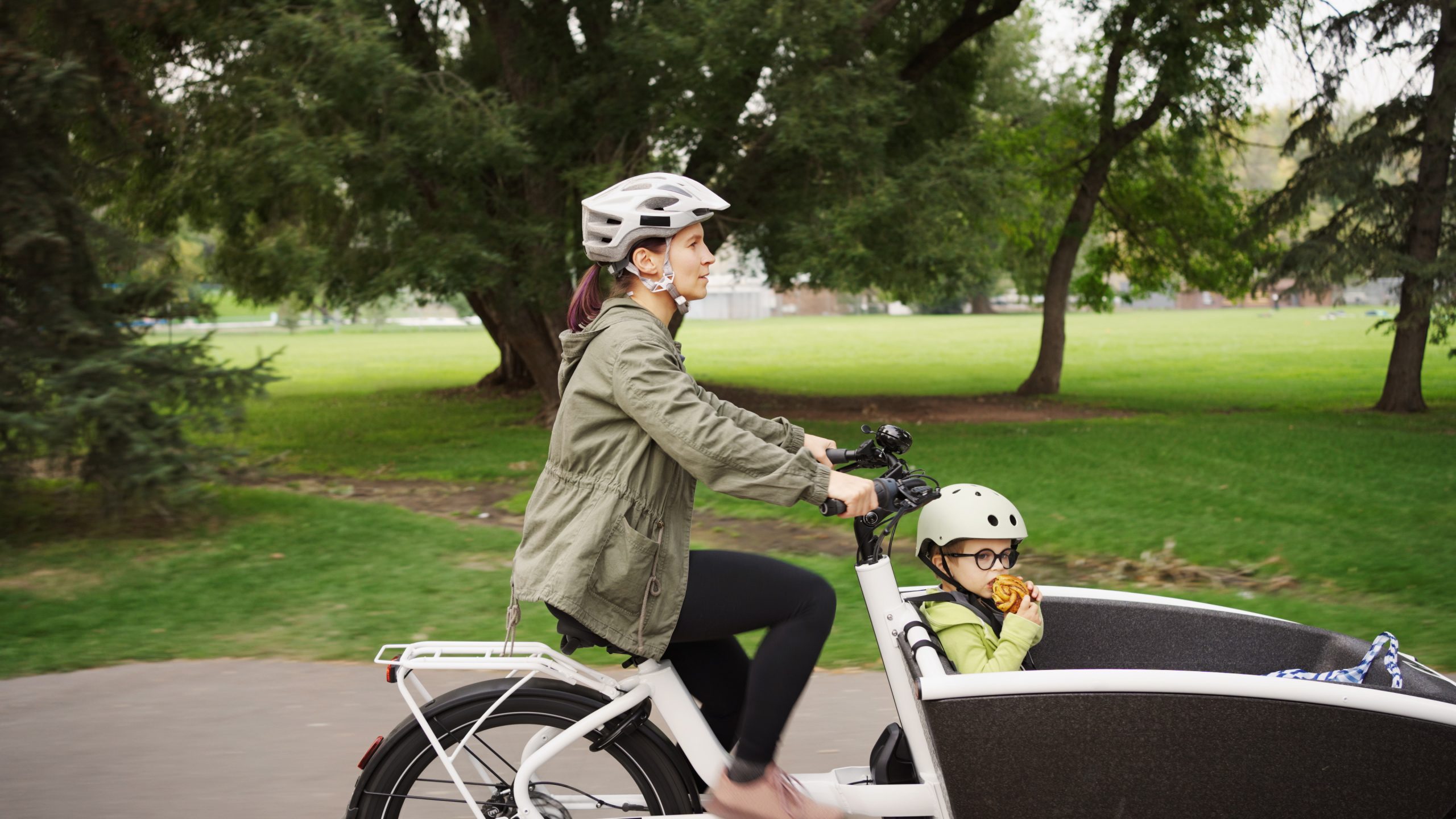 woman cycling a cargo bike with a child