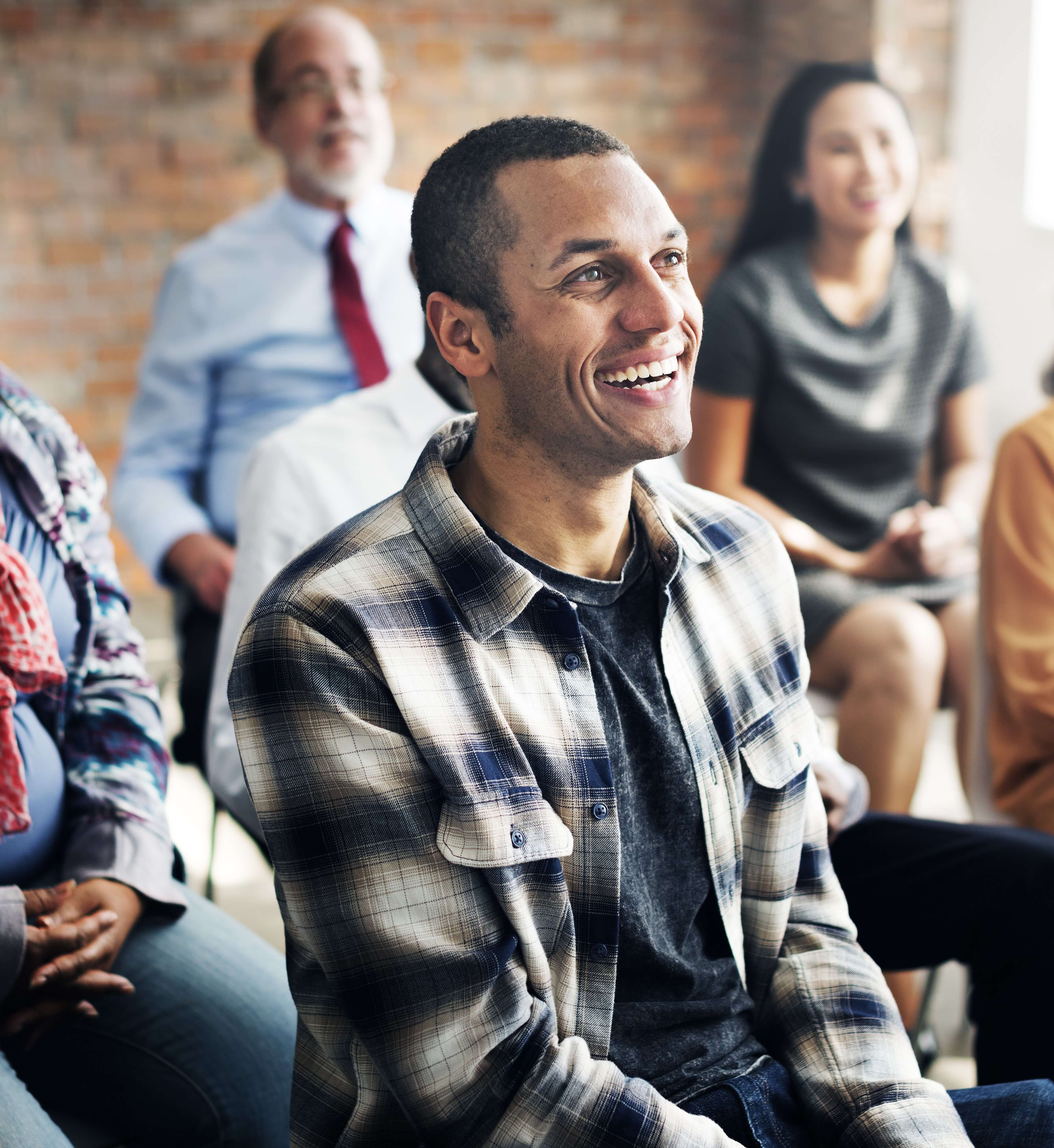 A man laughing in a seminar with people in the background