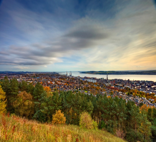 A view of Dundee from a hillside, the River Tay can be seen beyond the city