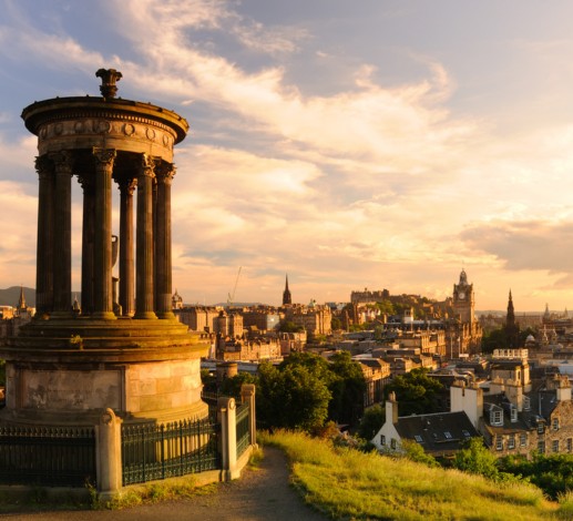 A view from Calton Hill in Edinburgh, the city below is lit by warm sunlight. 