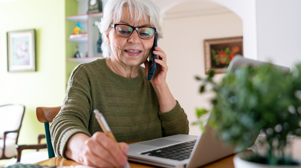 A person using the phone while taking notes
