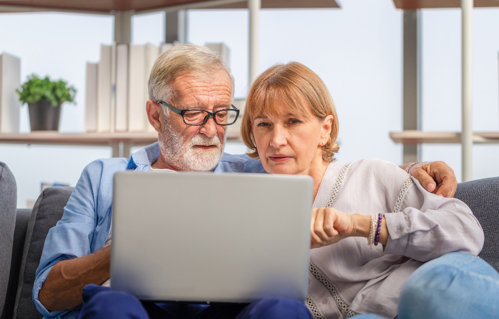 Senior couple looking concerned at energy bills and computer
