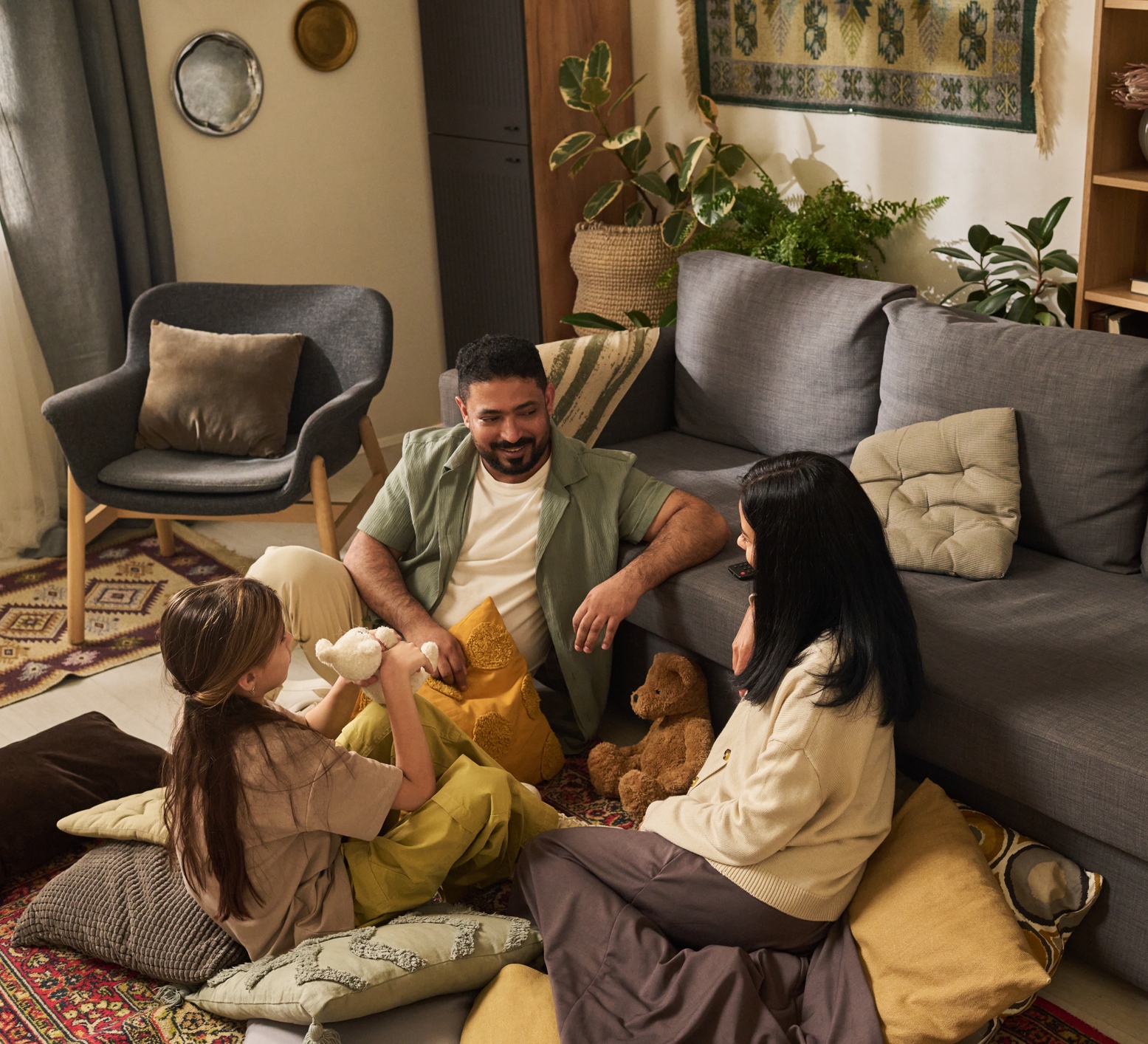 A child and two adults sitting on the floor in their home in a cosy setting
