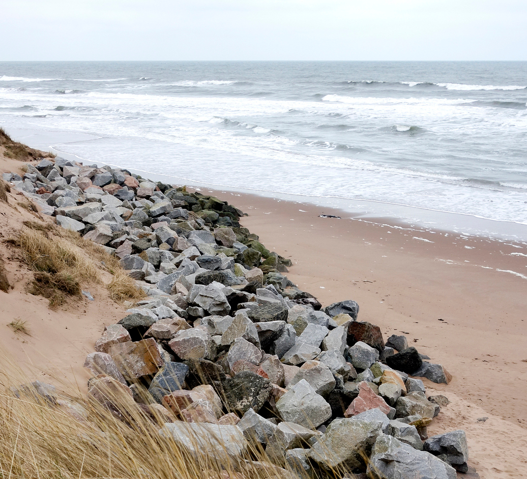 A beach with rocks lining the shores