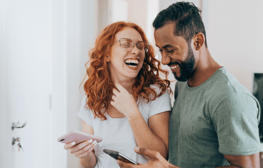 couple smiling at phones