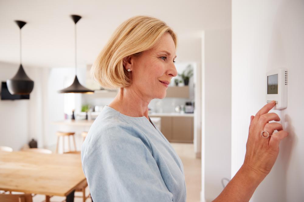 Woman adjusting central heating temperature