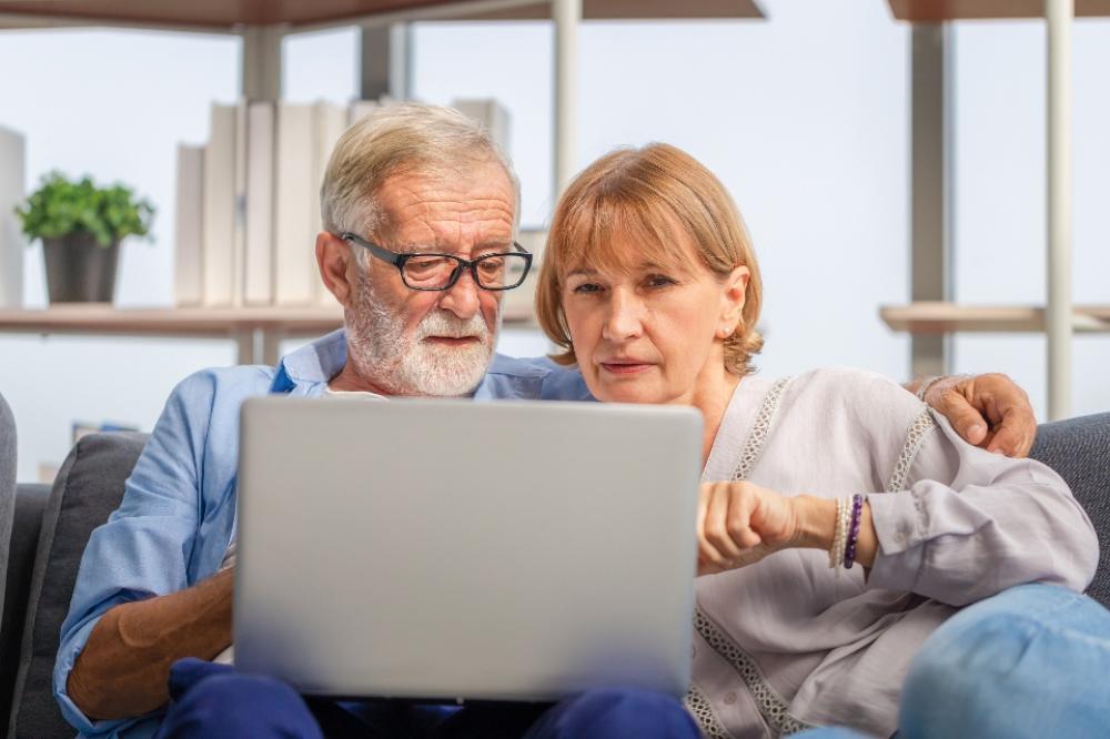 Senior couple looking concerned at energy bills and computer