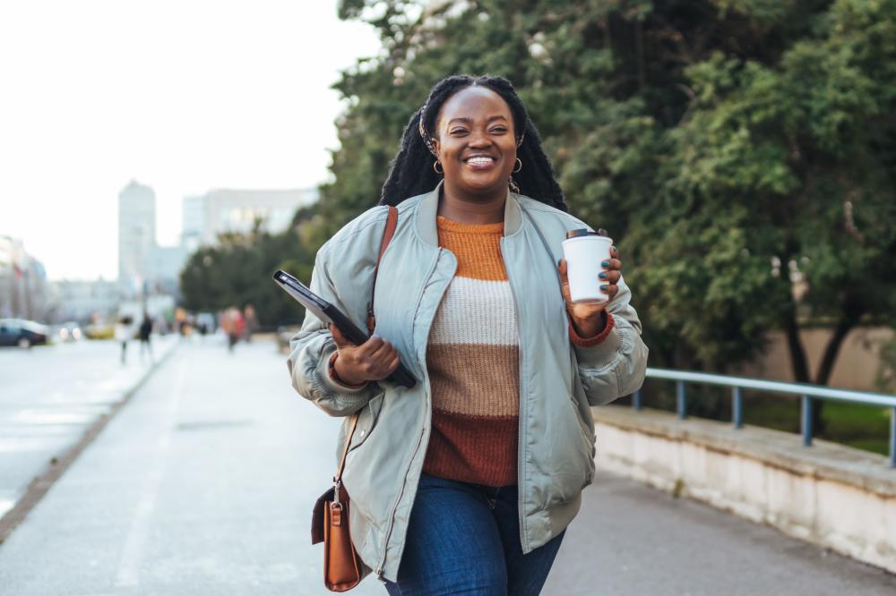 woman walking on the pavement carrying coffee