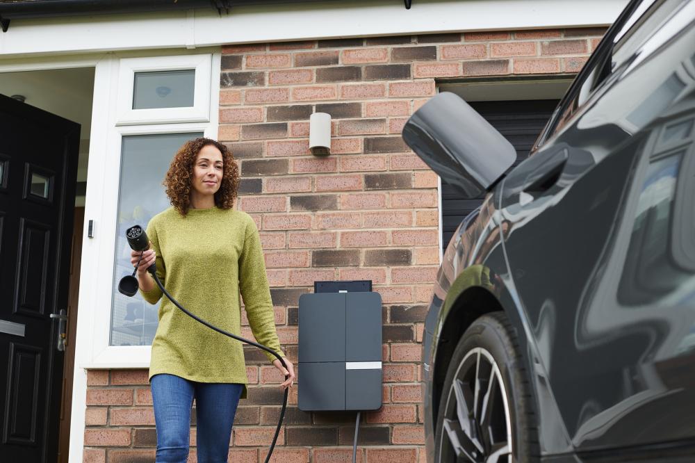 a woman charging an electric vehicle in a driveway