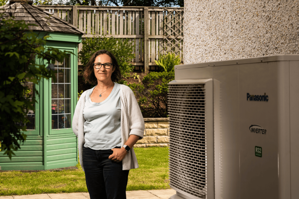 Ann standing beside her heat pump smiling