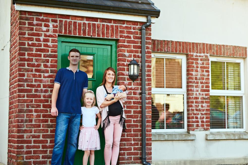 Young family standing outside their home