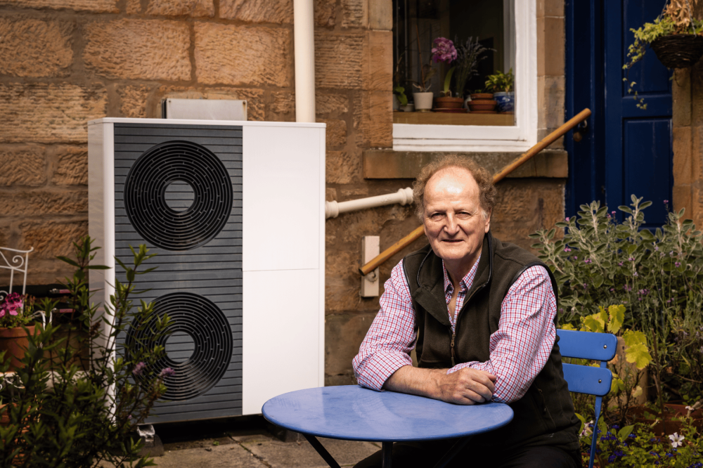 A man sitting at a table beside a heat pump