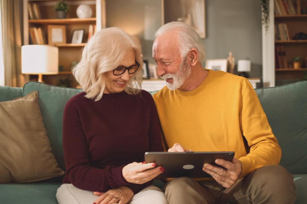 A cheerful older couple sitting on a sofa