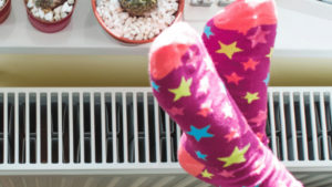 Feet in colourful socks warming on a radiator