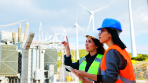 Two women in Engineering standing in front of some wind turbines